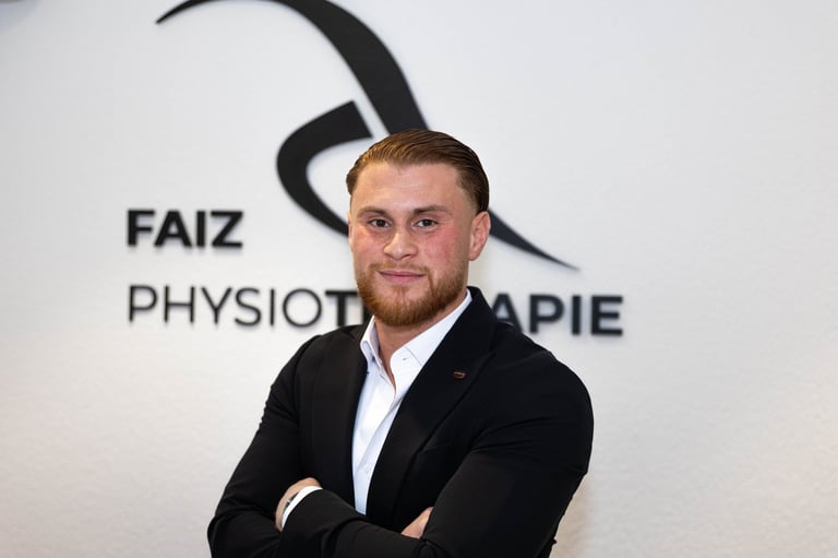 Mohammed Faiz, staatlich geprüfter Physiotherapeut, Gründer von Faiz Physiotherapie, im schwarzen Blazer vor der Praxis